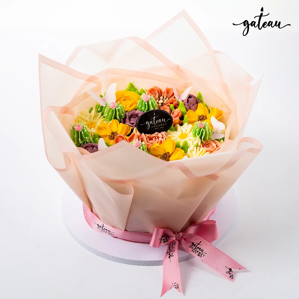 Floral cake decoration bundle with colorful buttercream flowers wrapped in translucent paper and pink ribbon