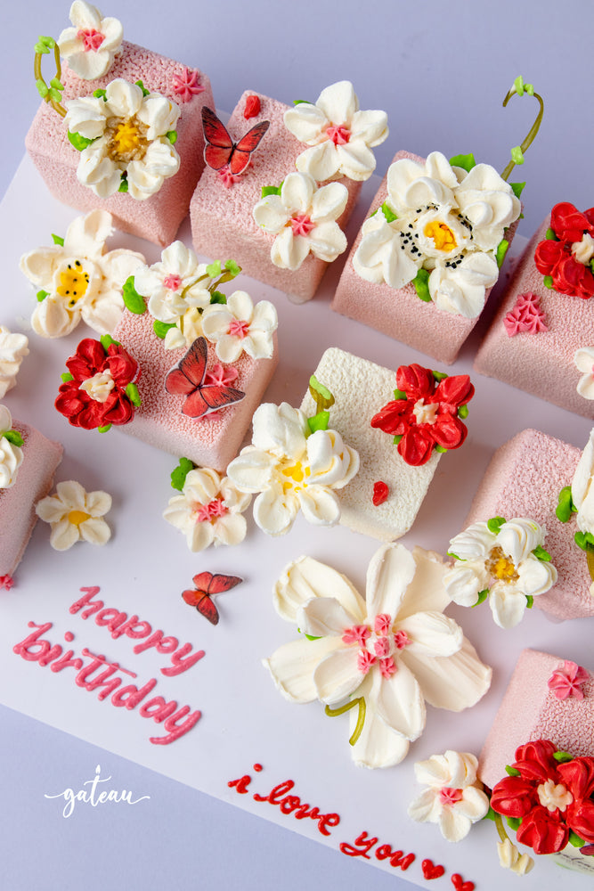 Floral decorated cake cubes from Gateau Gourmet Cafe with intricate white and red flower designs