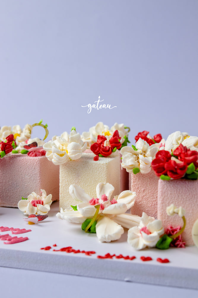 Floral decorated cake cubes by Gateau Gourmet Cafe with white and red flower icing on pink and white cakes