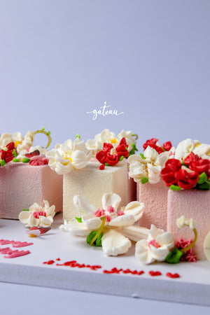 Floral decorated cake cubes by Gateau Gourmet Cafe with white and red flower icing on pink and white cakes