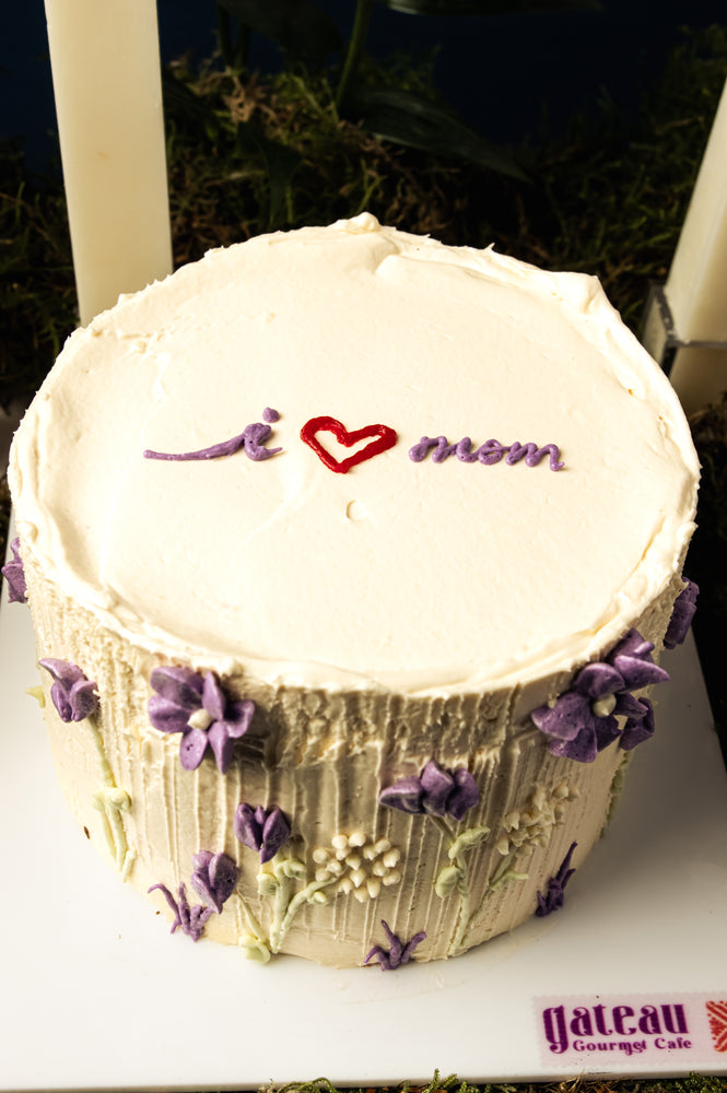 Floral Mother's Day cake by Gateau Gourmet Cafe with white frosting and purple flower decorations