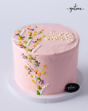 Pink flower bundle cake adorned with colorful icing flowers and 'Happy Birthday' message
