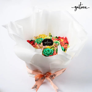 Flower decorated cupcakes arranged in a bouquet with colorful icing flowers wrapped in white paper