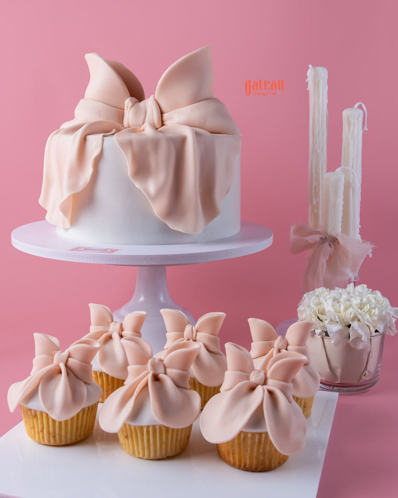 Elegant fondant cakes for celebrations with large bow design and matching cupcakes by Gateau Gourmet Cafe