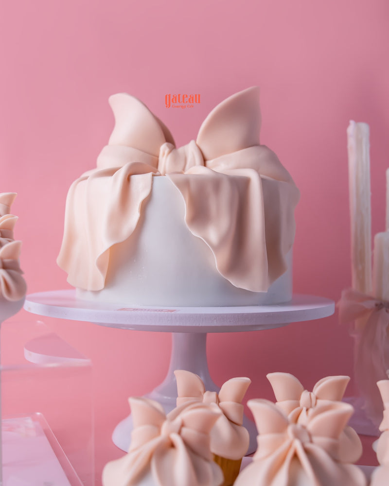 Elegant white fondant cake with large blush pink bow from Gateau Gourmet Cafe fondant cakes for celebrations