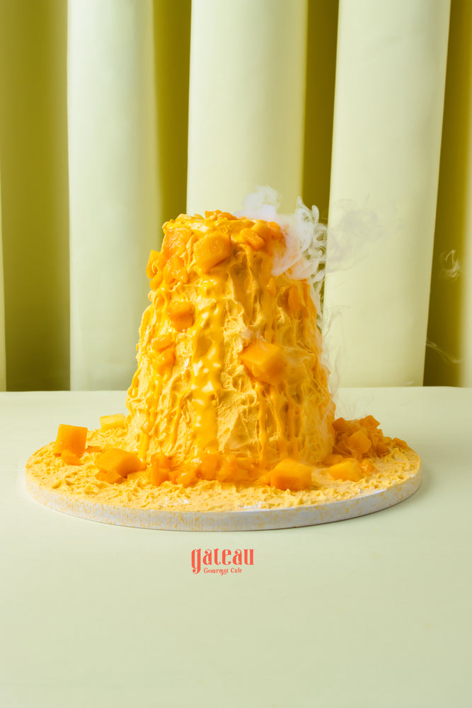 Fresh mango layered cake from Gateau Gourmet Cafe topped with mango chunks on white plate