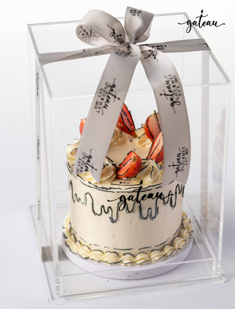 Beautifully packaged fresh strawberry cake with decorative frosting and strawberries on top
