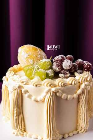 Gateau Gourmet Cafe fruit topped birthday cake decorated with grapes and lemon on creamy frosting