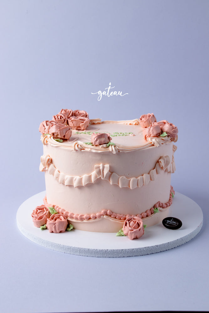 Elegant cake with full-bloom-rose-design, featuring pink roses and decorative piping on a light background