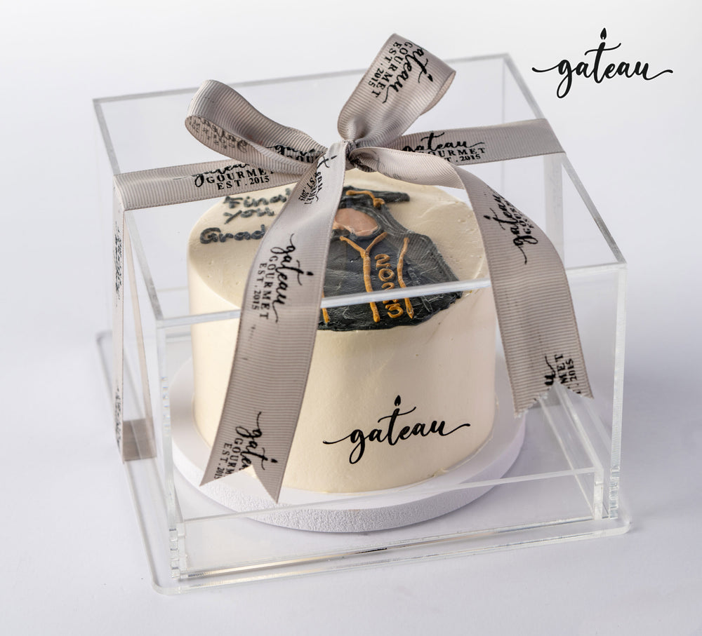 Gild graduation celebration cake in a clear box with a decorative ribbon for festive occasions
