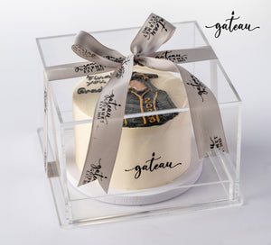 Gild graduation celebration cake in a clear box with a decorative ribbon for festive occasions
