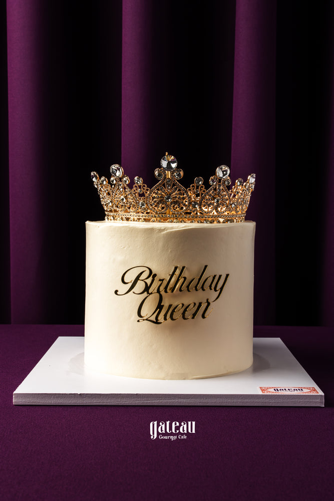 Gourmet birthday cake from Gateau Gourmet Cafe with elegant white frosting and ornate golden crown topper