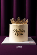 Gourmet birthday cake from Gateau Gourmet Cafe with elegant white frosting and ornate golden crown topper