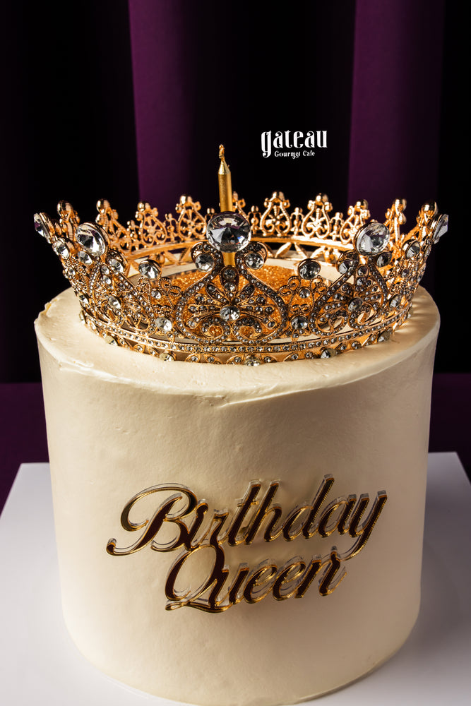Gateau Gourmet Cafe gourmet birthday cake with white frosting and decorative gold crown topper