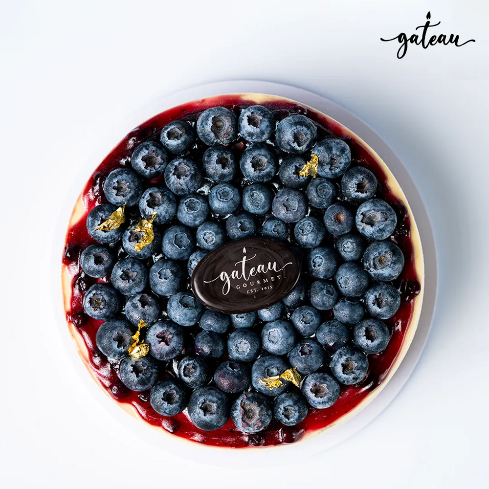 Gateau Gourmet Cafe gourmet blueberry cheesecake topped with fresh blueberries and gold leaf accents