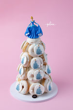 Gourmet donut tower with white frosted donuts featuring Cinderella design topped with a Cinderella figurine