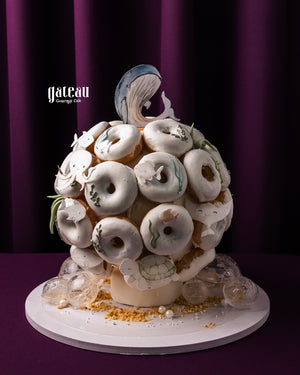 Unique cake from Gateau Gourmet Cafe decorated with white donuts featuring ocean-themed designs for gourmet donuts delivery