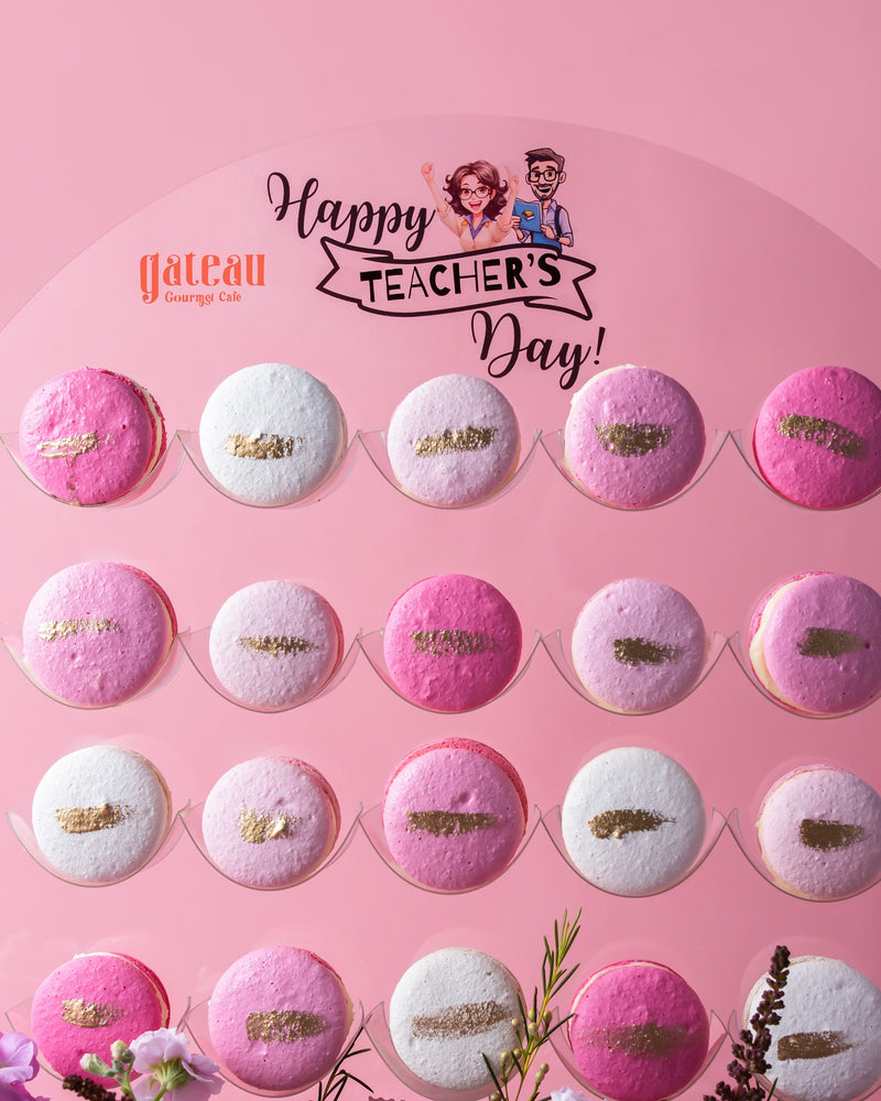 Gourmet macaroons with stand in pink and white colors arranged on a Happy Teacher's Day display board