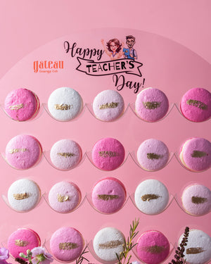 Gourmet macaroons with stand in pink and white colors arranged on a Happy Teacher's Day display board