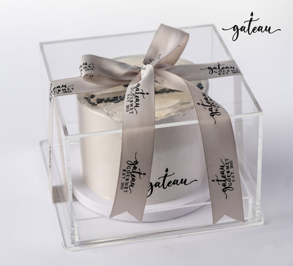Elegant graduation celebration cake presented in a clear box with stylish ribbon from Gateau Gourmet Cafe