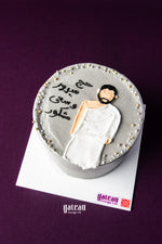 Hajj celebration cake by Gateau Gourmet Cafe with gray frosting and man in white Ihram robe decoration