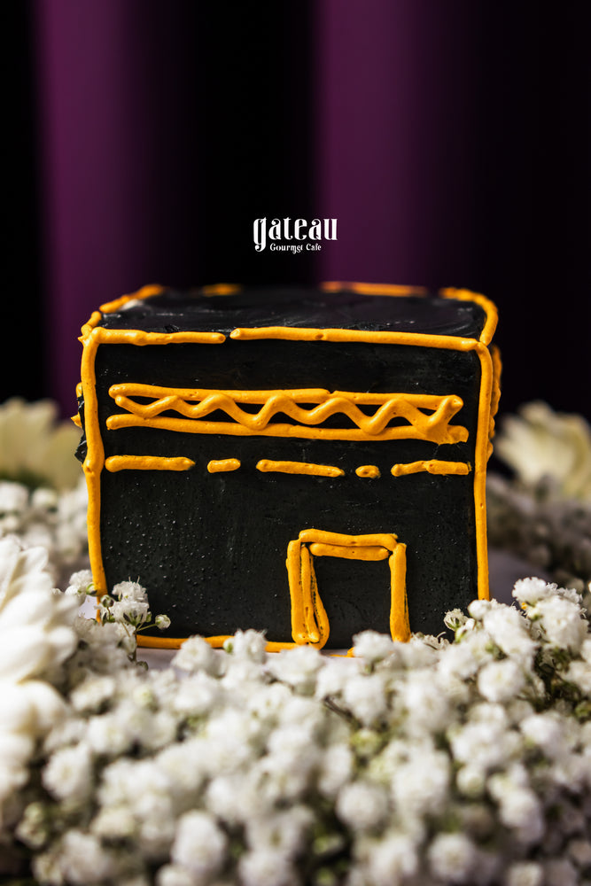 Hajj celebration cake by Gateau Gourmet Cafe shaped like Kaaba with black icing and decorative orange lines