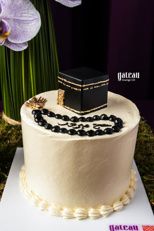 Gateau Gourmet Cafe Hajj celebration cake with black Kaaba decoration and prayer beads on white frosting