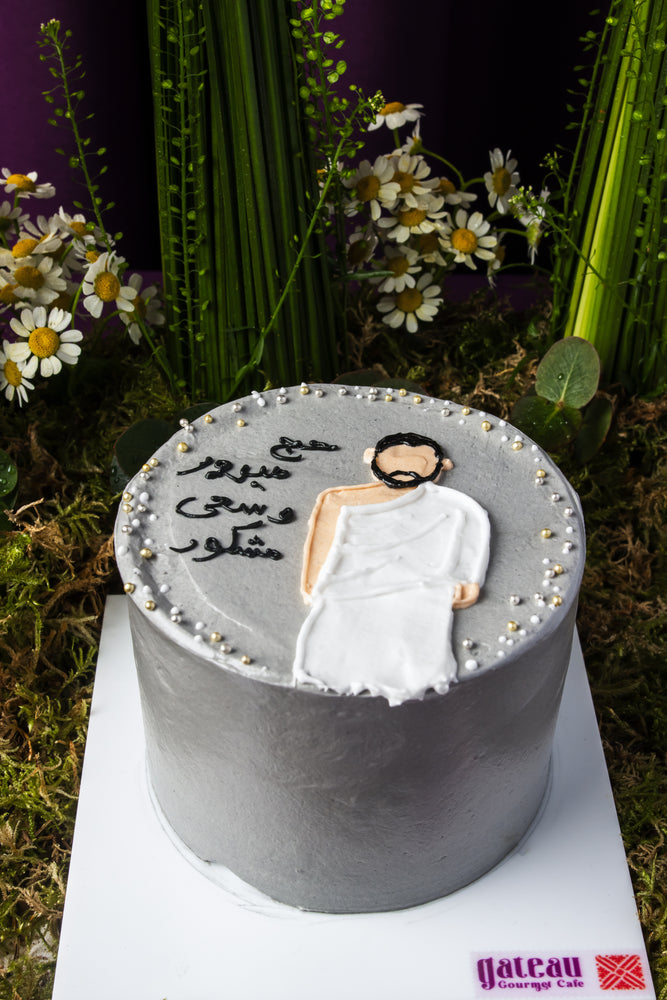 Hajj celebration cake by Gateau Gourmet Cafe with gray icing and a figure wearing Ihram robes