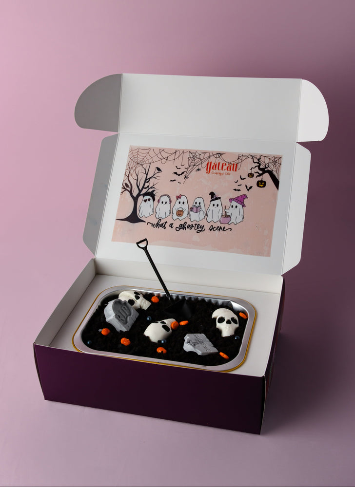Halloween loaf cake decorated with spooky skulls and orange accents in an elegant gift box