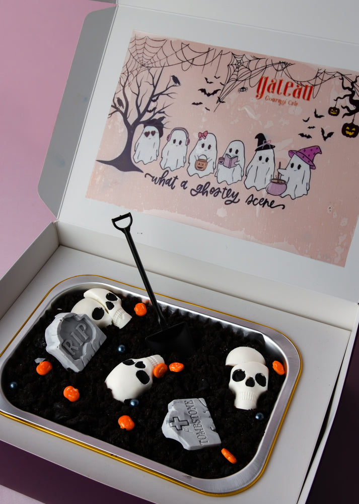 Halloween loaf cake with spooky decorations including ghosts, tombstones, and candy accents