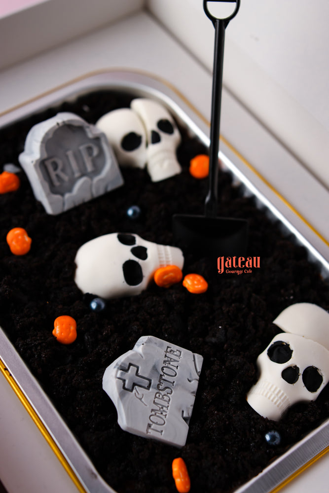 Halloween loaf cake with spooky decorations like skulls, tombstones, and candy pumpkins