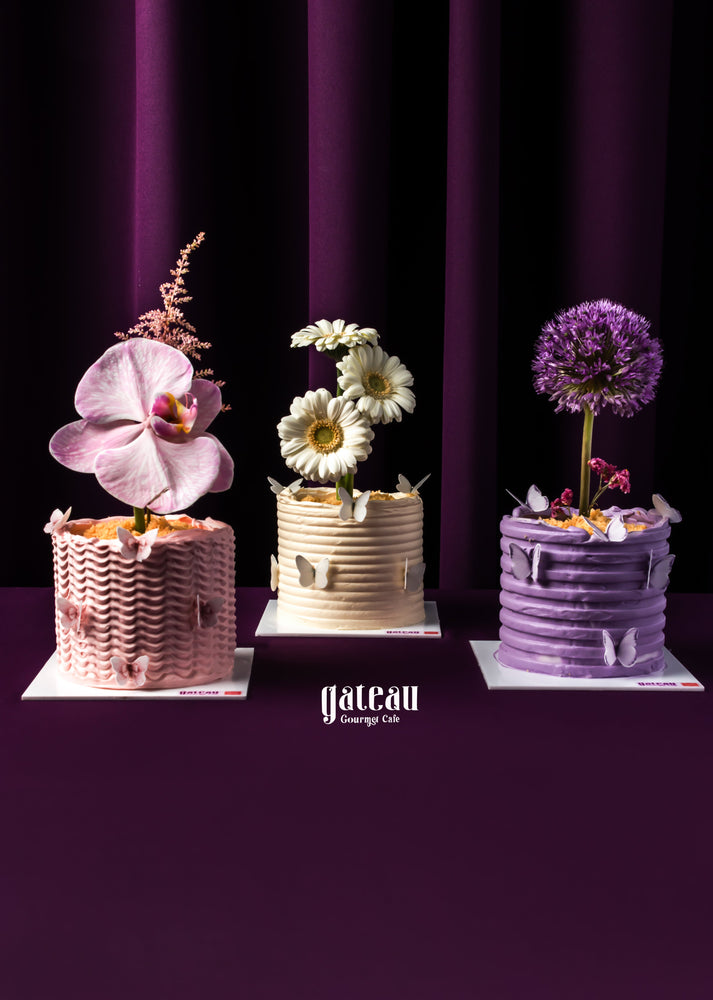 Handcrafted birthday cake assortment from Gateau Gourmet Cafe with floral decorations in pink, white, and purple