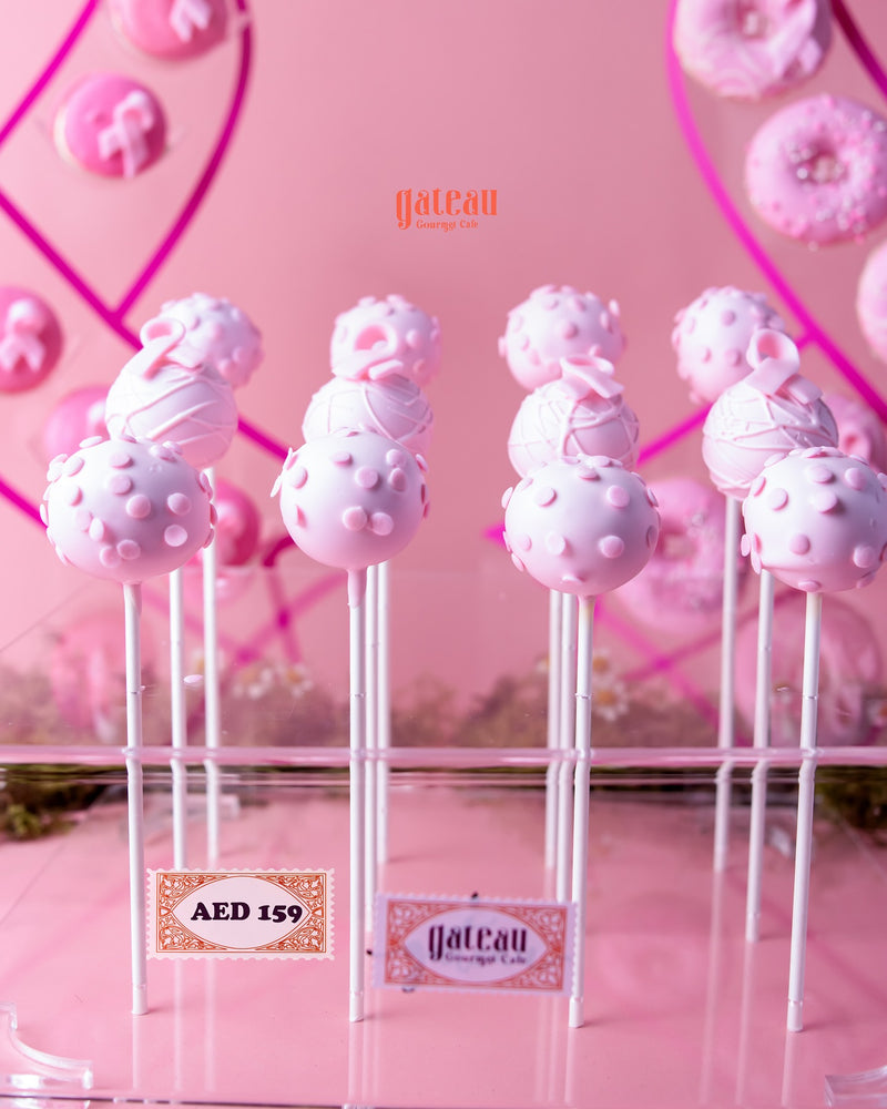 Pink handcrafted cake pops on sticks with decorative patterns from Gateau Gourmet Cafe