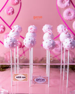 Pink handcrafted cake pops on sticks with decorative patterns from Gateau Gourmet Cafe