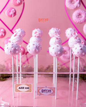 Pink handcrafted cake pops on sticks with decorative patterns from Gateau Gourmet Cafe
