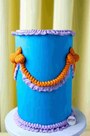 Blue tall cake with orange and purple frosting decorations by Gateau Gourmet Cafe handcrafted cakes near me