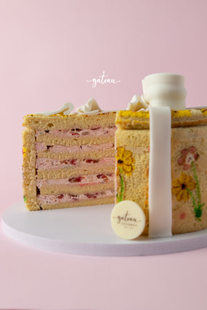 Handcrafted gourmet cake with layered strawberry filling and floral decorations by Gateau Gourmet Cafe