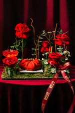 Heart shape mousse cake from Gateau Gourmet Cafe surrounded by red roses and decorative greenery on a red velvet surface