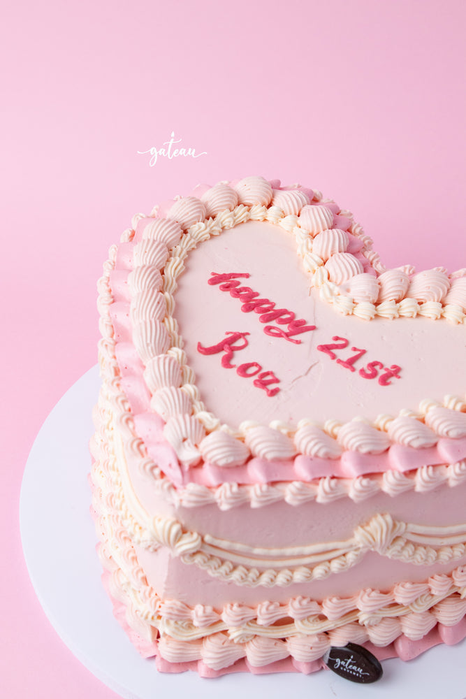 Pink heart shaped cake with layered frosting and red writing for a 21st birthday celebration