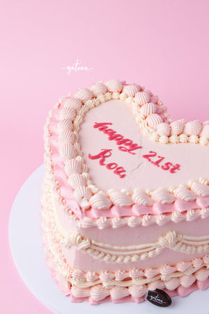 Pink heart shaped cake with layered frosting and red writing for a 21st birthday celebration