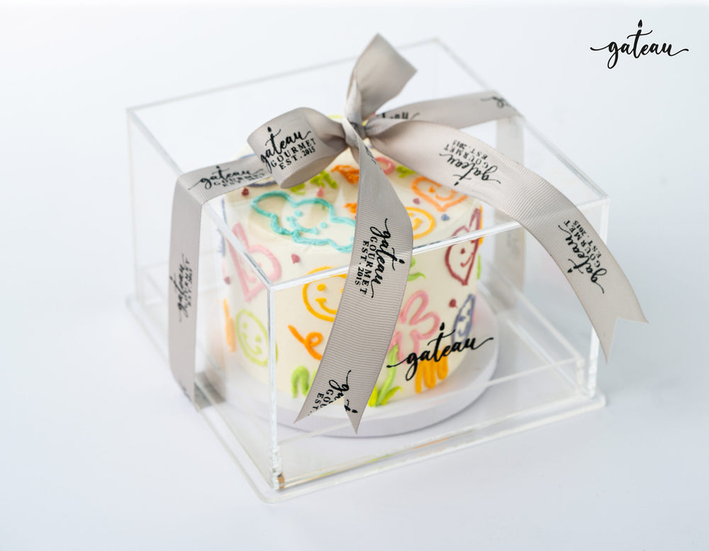 Hippie sticker cake from Gateau Gourmet Cafe beautifully wrapped in a clear box with a ribbon