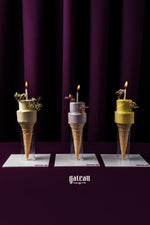 Gateau Gourmet Cafe ice cream cone cake with candles in multiple colors displayed on white plates against a dark purple background