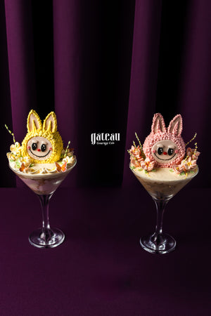 Two colorful Labubu cake desserts topped with bunny decorations served in glass bowls
