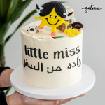 Little miss buttercream cake topper on white frosted cake with Arabic writing and playful design