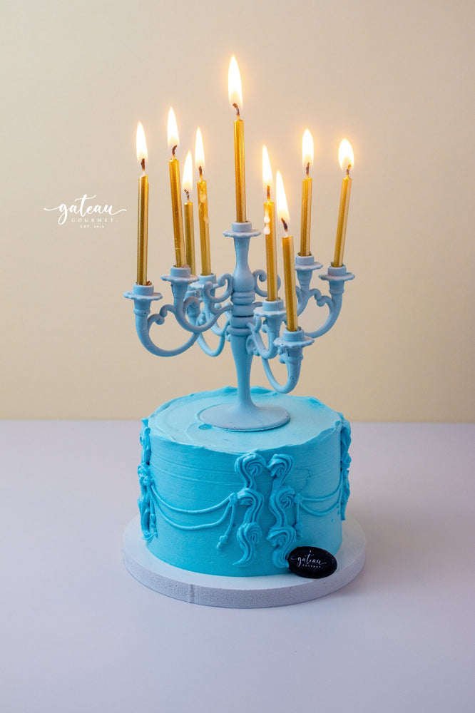 Luxury candelabra cake by Gateau Gourmet Cafe with blue frosting and lit gold candles