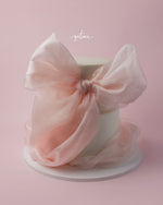 Luxury celebration cakes from Gateau Gourmet Cafe featuring elegant white cake with large pink bow