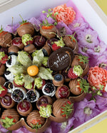 Luxury chocolate dipped fruits assortment including strawberries, cherries, and berries with decorative flowers by Gateau Gourmet Cafe