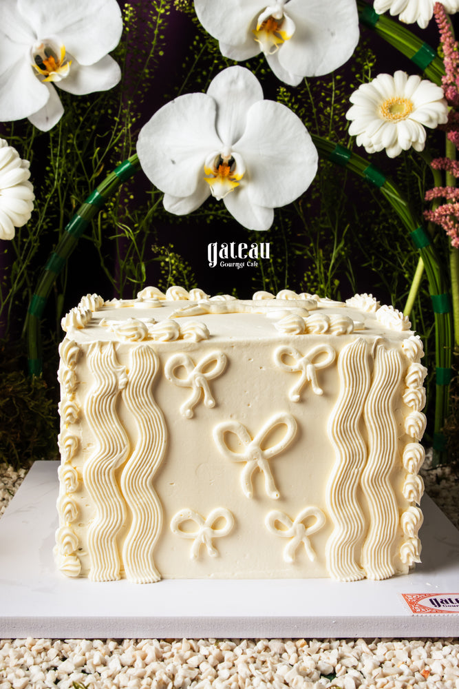 Luxury floral cake display by Gateau Gourmet Cafe featuring white floral decorated square cake