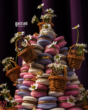 Colorful macaroon tower centerpiece with purple, pink, and white macaroons decorated with small wicker baskets and white flowers