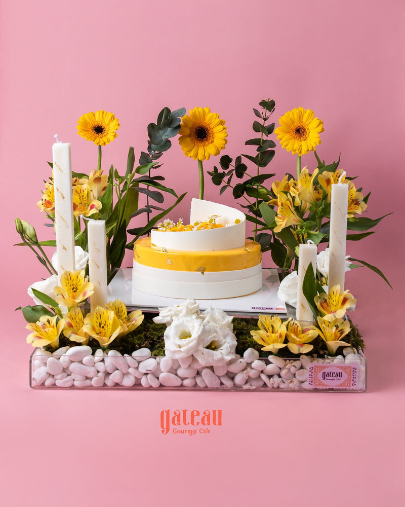 Mango mousse cake arrangement with vibrant flowers and decorative accents for a festive celebration